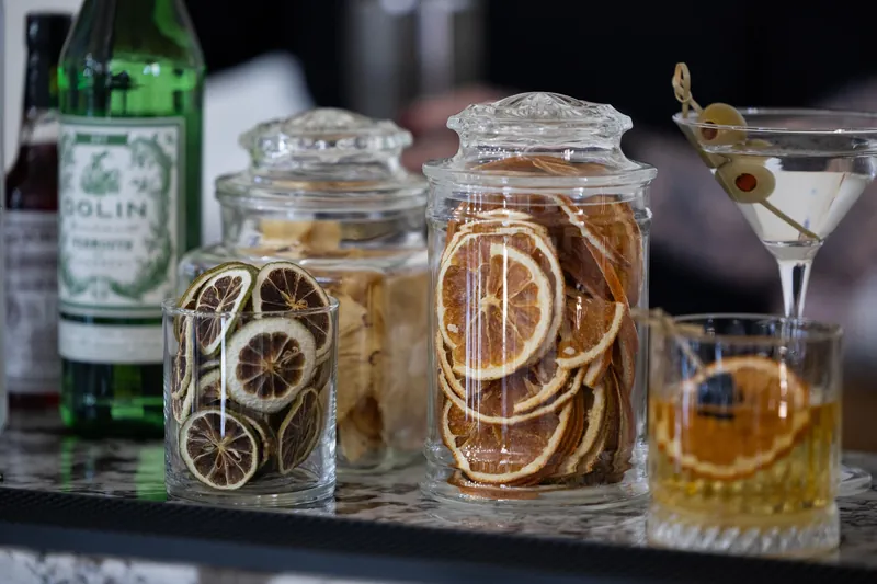 Jars of dried citrus slices and drinks on a bar counter