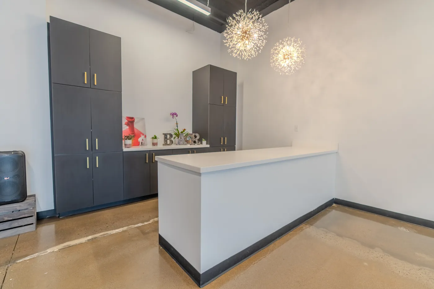 The bar counter and storage cabinets along one wall of the event space